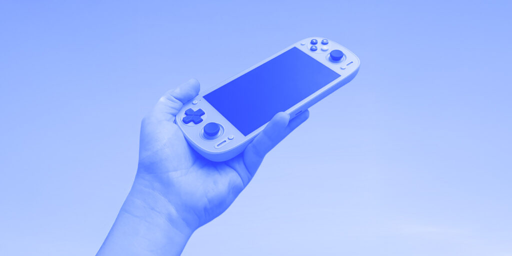 A blue tinted image of a hand holding a Retroid Pocket G2
